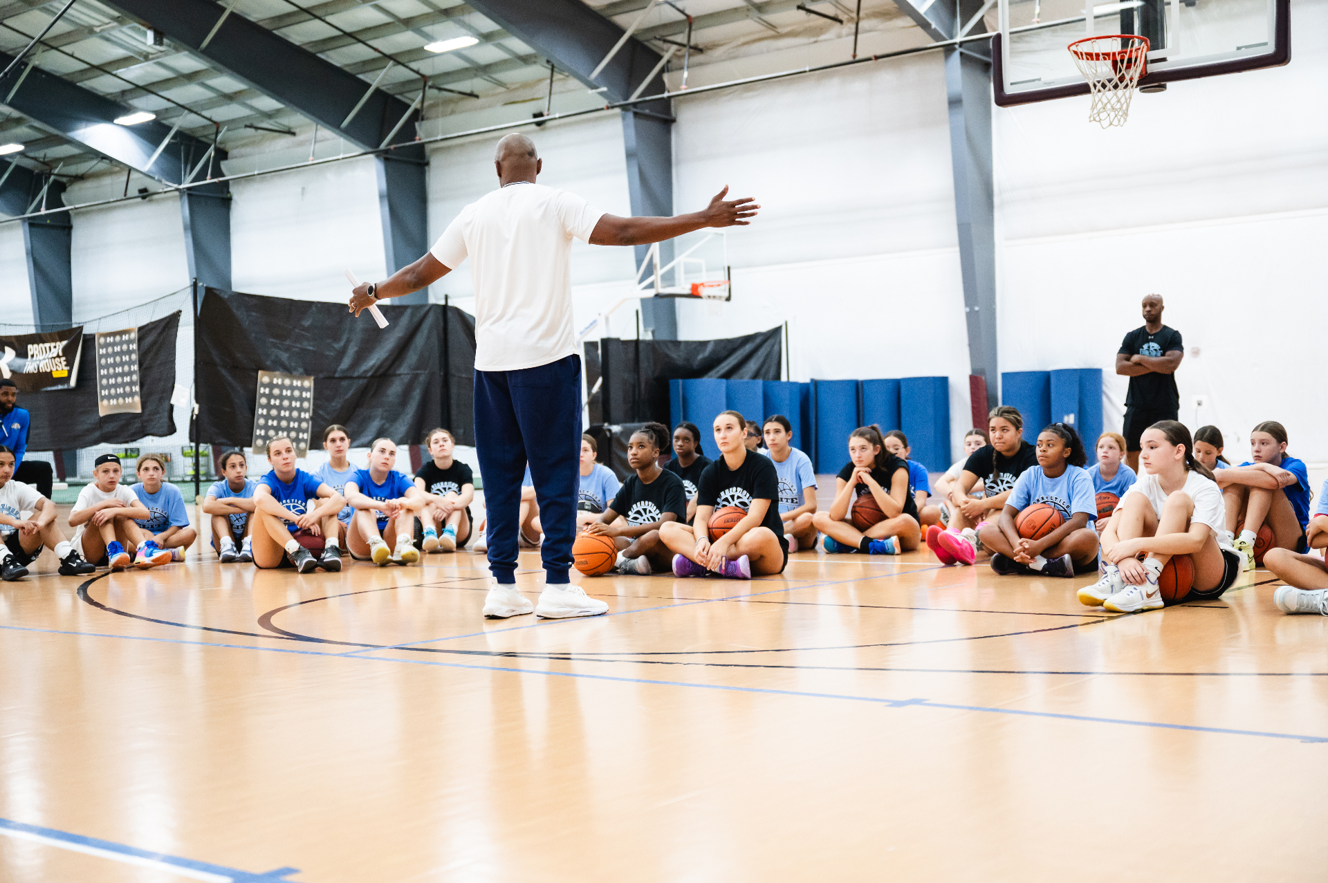 Connecticut Elite head coach addressing a group of players seated at center court